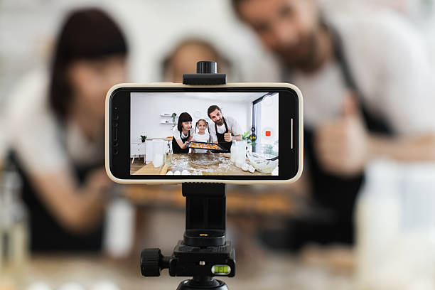 istock Caucasian family recording baking tutorial with smartphone in a modern kitchen 2208927818