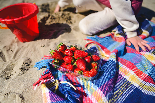 istock Child playing on the beach with strawberries and a red bucket 2208929013