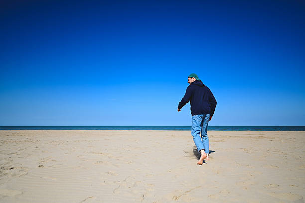 Man enjoying a sunny day at the beach, walking barefoot on the sand