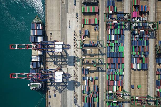 istock Vertical top down view of cargo containers piled on the quayside and cranes unloading the goods from a ship, which is parking at the dock of Taipei Harbor in Bali District, New Taipei City, Taiwan 2208933173