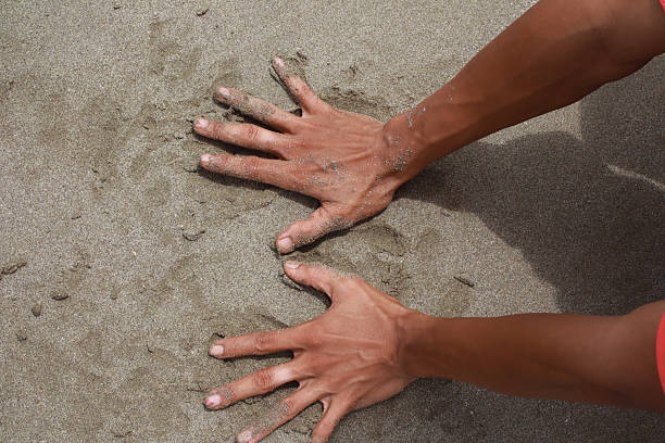 istock Sandy Imprints: A man's palms press into the texture of the beach sand, making temporary marks 2208933640