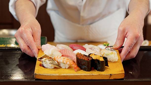 Chef's hands offering nigiri sushi