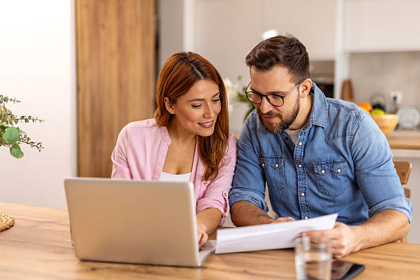 istock A couple is sitting at a table, using a laptop together. The scene captures teamwork, communication, or shared activities in a home or work setting, reflecting modern technology and collaboration 2208937534