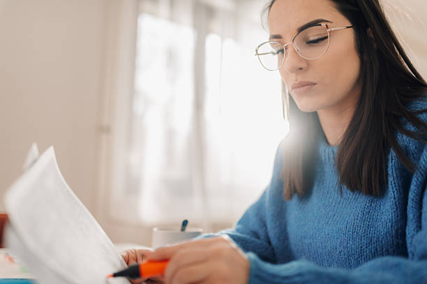 istock Young woman reviewing documents at home with a highlighter 2208939182