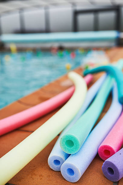 istock Colorful foam pool noodles on deck by indoor swimming pool 2208940188