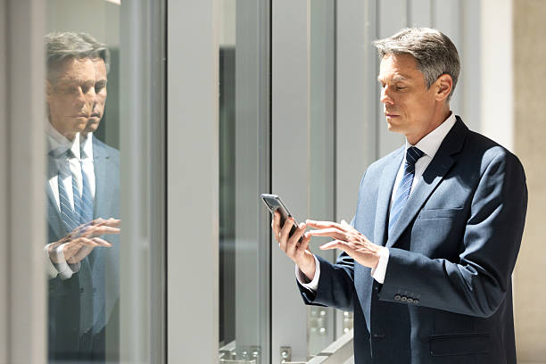 istock Serious senior management businessman using his phone in office 2208940532
