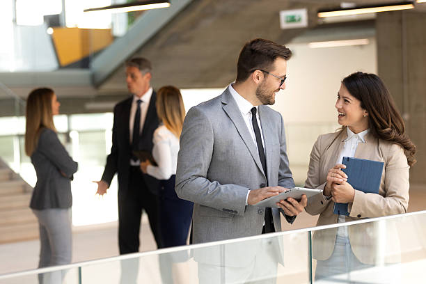 istock Two coworkers having a discussion in modern lobby while looking at document and digital tablet 2208940721