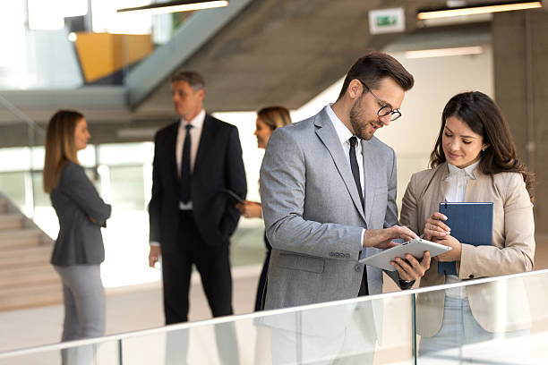 istock Two coworkers having a discussion in modern lobby while looking at document and digital tablet 2208940726