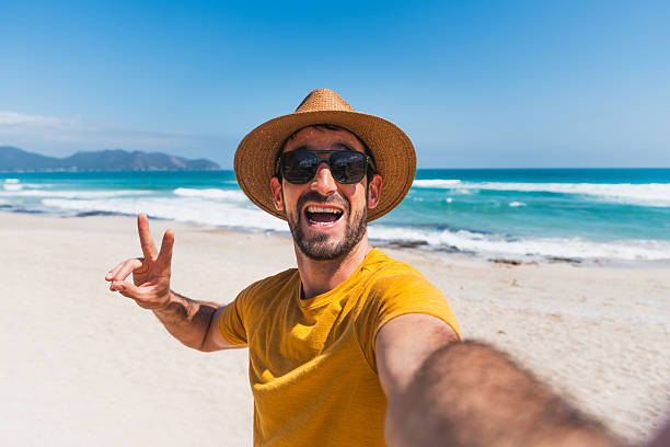 istock Young man taking selfie on sunny beach vacation 2208942313