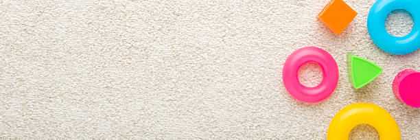 istock Different colorful plastic playing shapes on white soft home carpet background. Closeup. Baby development toys. Wide banner. Empty place for text. Top down view. 2208944358