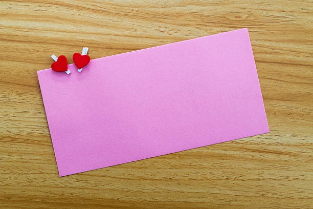 Pink envelope and hand holding a pink heart on pink background. Front view.