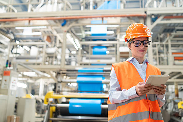 istock Engineer overseeing operations on tablet in bright industrial plant wearing safety gear. 2208944865