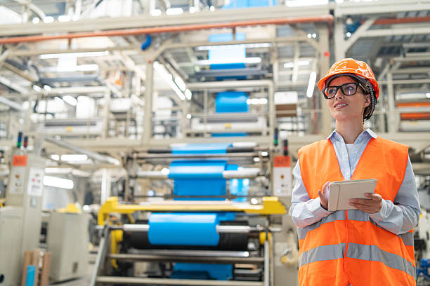 istock Engineer overseeing operations on tablet in bright industrial plant wearing safety gear. 2208944882