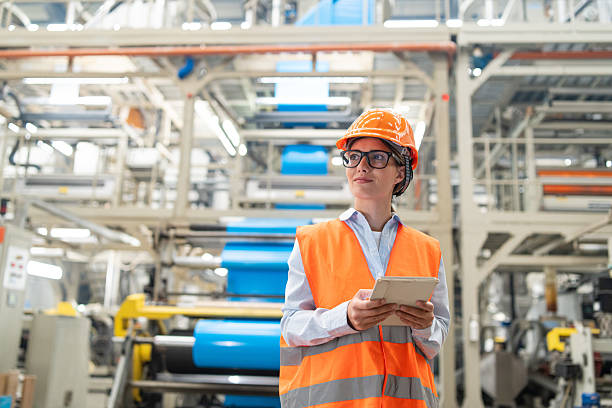 istock Engineer overseeing operations on tablet in bright industrial plant wearing safety gear. 2208944895