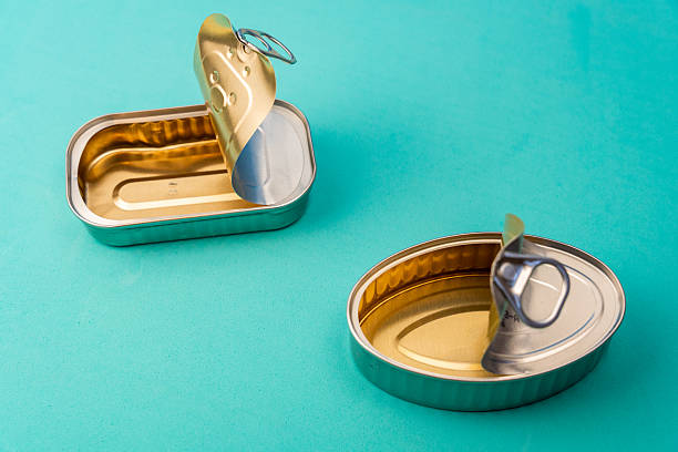 istock Metallic tin cans standing open, golden interior gleaming against turquoise surface, displaying clean minimalist aesthetic 2208950326