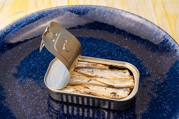 istock Sardine tin resting on bright blue plate, glistening with olive oil, highlighting compact seafood protein source 2208950621