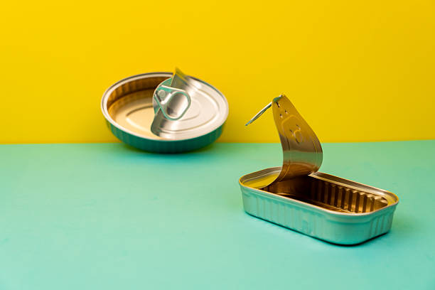 Empty and opened cans resting on a vibrant yellow and light blue background, awaiting filling with delicious contents