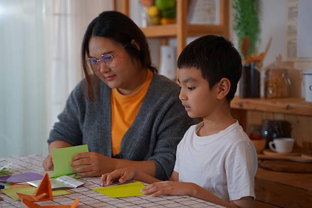 istock Mother teaching her child flowing paper in the kitchen. 2208952204