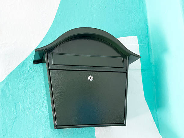 istock Black wall-mounted mailbox with lock on brightly painted turquoise and white wall 2208953867