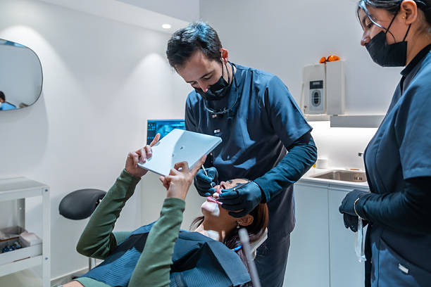 istock Dentist performing teeth whitening procedure on patient in modern clinic 2208953894