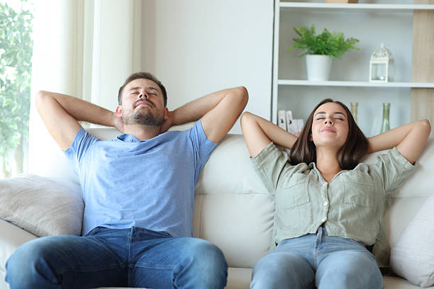 istock Happy couple at home relaxing and resting on a couch 2208955088