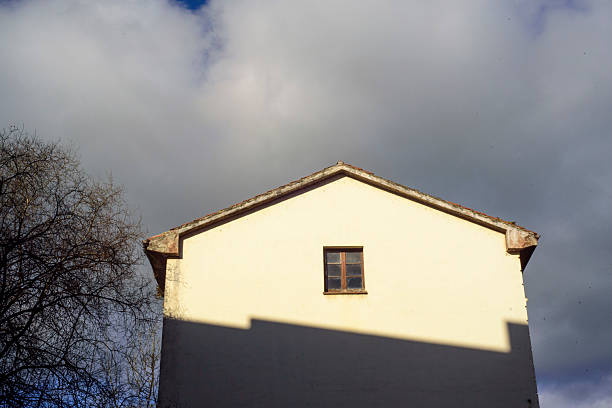 Looking up at newly installed white aluminum fascia and vinyl perforated soffit on an addition to a residential home with lens flare from the sun.