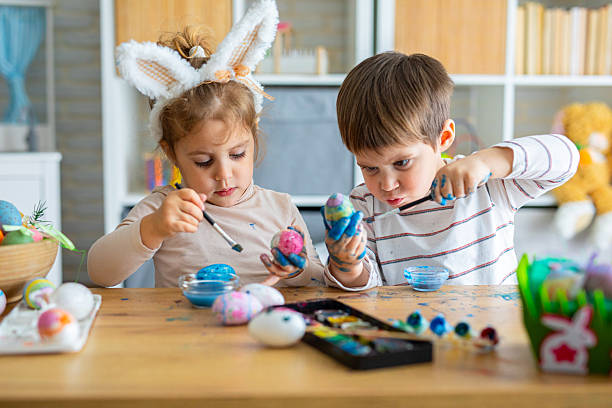 istock Kids having fun and playing while painting eggs for Easter holiday 2208960230