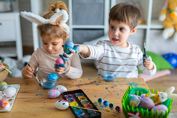 istock Kids having fun and playing while painting eggs for Easter holiday 2208960251