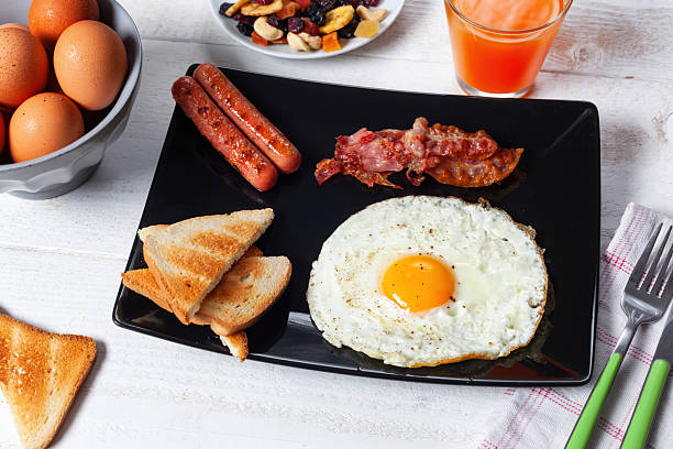 istock Delicious full English breakfast with fried egg, bacon, sausages and toasts 2208961468