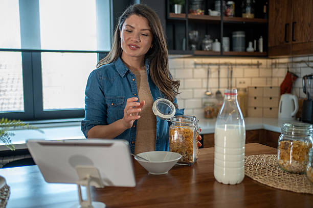istock Young woman preparing breakfast and following a recipe on a tablet in a modern kitchen 2208963338