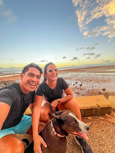 istock Couple Enjoying Sunset at Beach with Pet Dog 2208976047