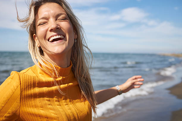 Happy woman enjoying day on a beach. It’s autumn and sun, perfect combination for vacation!