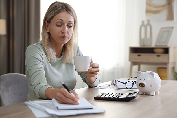 istock Budget planning. Woman with cup of drink taking notes at table indoors 2208979311