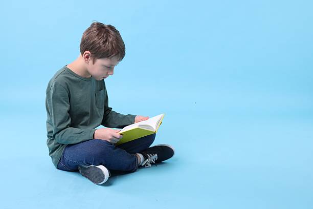 istock Boy with incorrect posture reading book on light blue background 2208979530