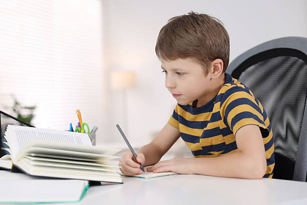 istock Boy with incorrect posture doing homework at white desk indoors 2208979540