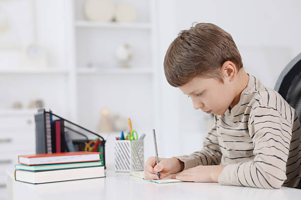 istock Boy with incorrect posture doing homework at white desk indoors 2208979578