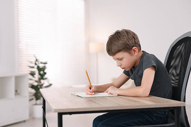istock Boy with incorrect posture using laptop at wooden desk indoors 2208979767