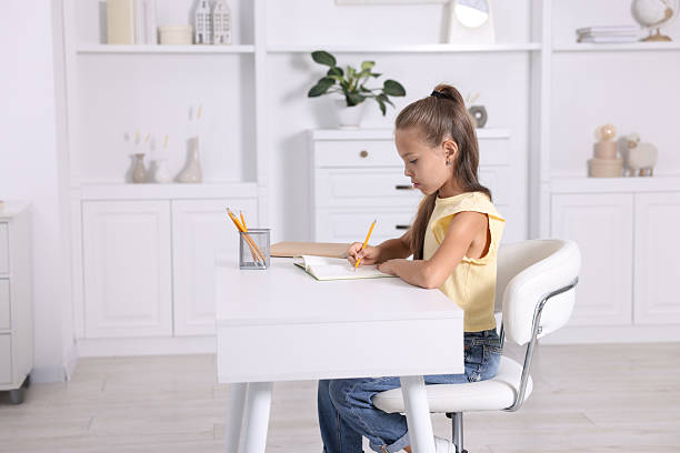 istock Girl with correct posture doing homework at white desk indoors 2208979771