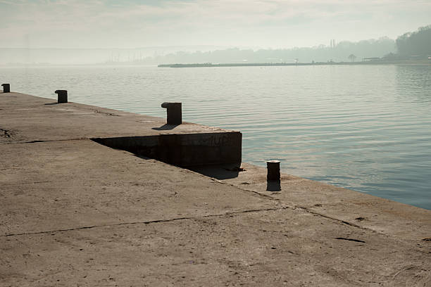 Layered image of the Varna's bay in fog. Quay with bollards in the foreground. Varna's sea port and harbor are in the distance. Bulgaria, Eastern Europe.