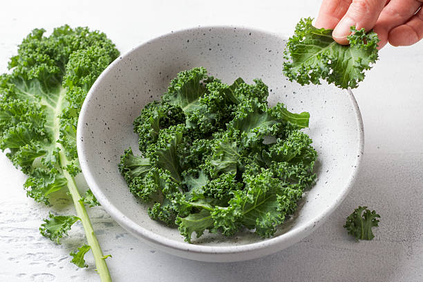 istock Fresh organic kale leaves in ceramic bowl ready for salad preparation on light kitchen table 2208983590