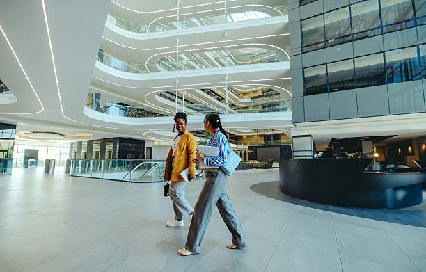 istock Two female corporate professionals walking in modern office lobby 2208990447