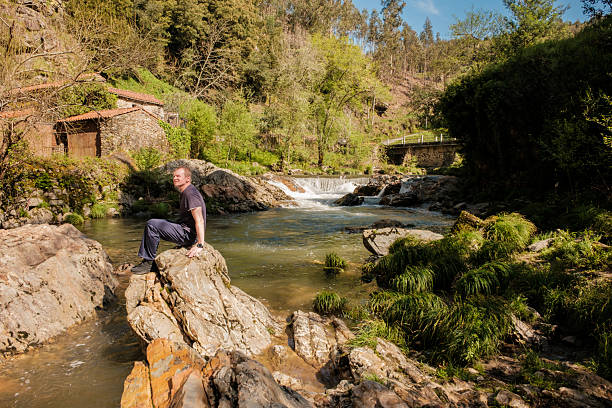 Hiker enjoying the tranquility of nature while sitting on a rock by a river