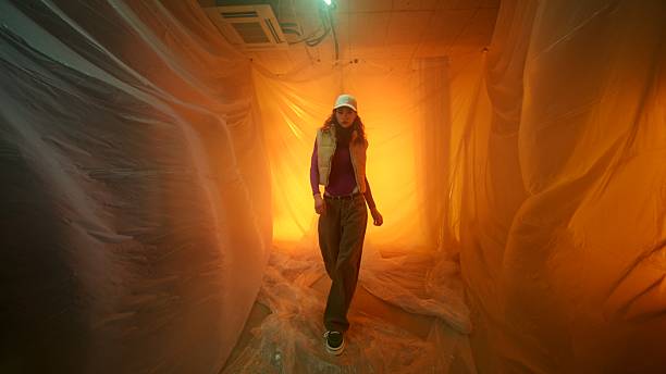 istock Woman Walking Through Ethereal Space with Orange Lighting and Draped Fabric 2208997026
