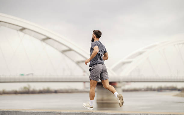 istock Rear view of fit runner running fast near river. 2209001572