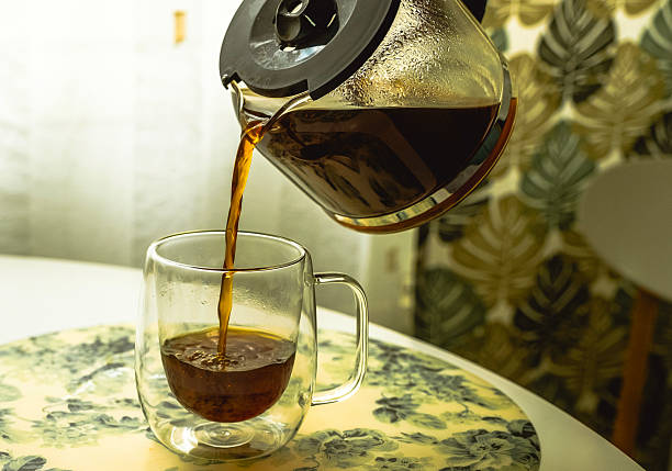 istock Coffee is poured into a glass mug from a glass coffee pot. 2209001965