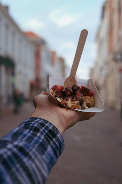 istock hand holding belgian waffle in city 2209009390