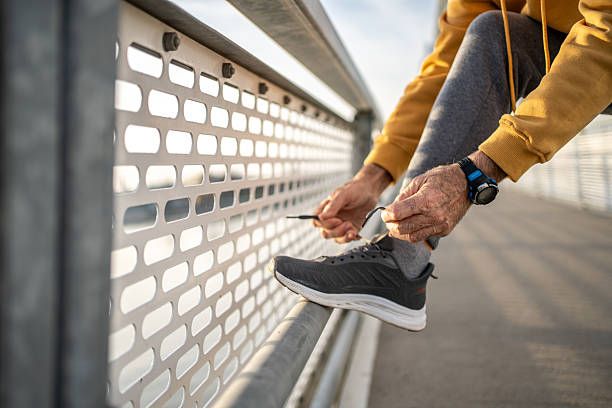 istock Senior man tying shoelaces before running on bridge 2209014839