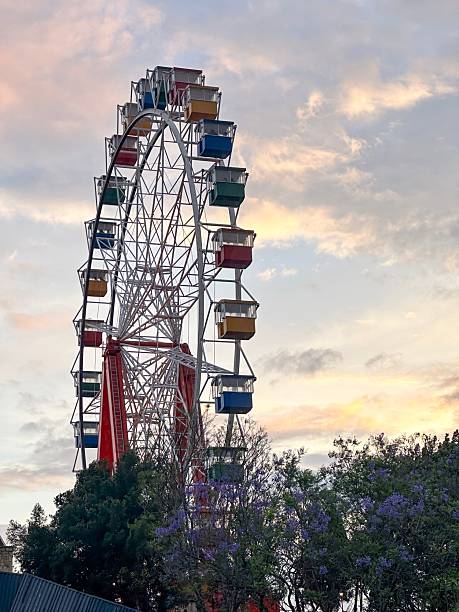 istock Ferris wheel against a vibrant sunset sky with trees in the foreground 2209016826