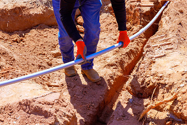 istock Worker installs plumbing pipe in a trench during daytime construction project in rural area 2209017606