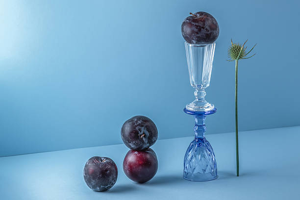istock Still life with ripe plums and glass glasses on a blue background. 2209018232